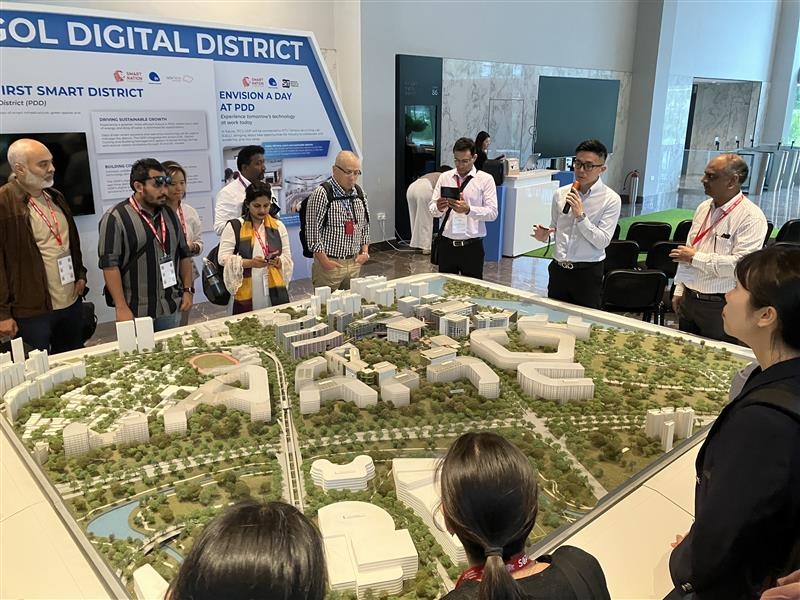 中央の都市模型を10名程度の研修員が囲んで見学している。